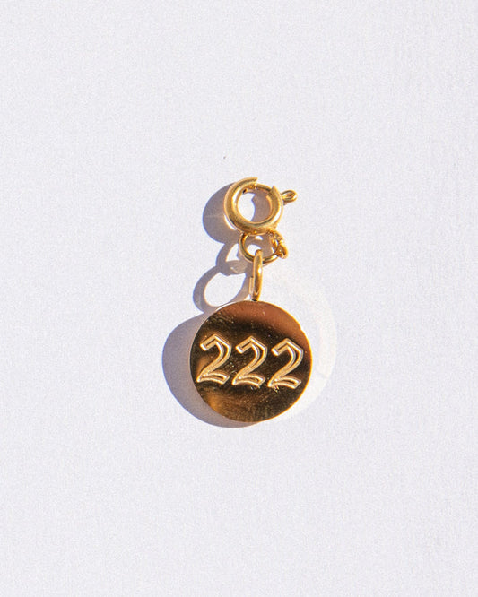 Gold circle charm with angel numbers '222' on a white background