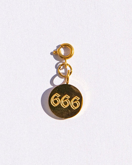 Gold circle charm with angel numbers '666' on a white background