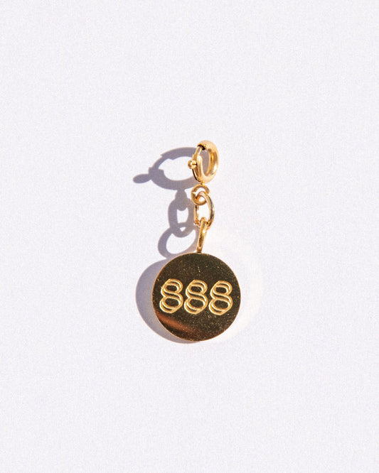Gold circle charm with angel number '888' on a white background