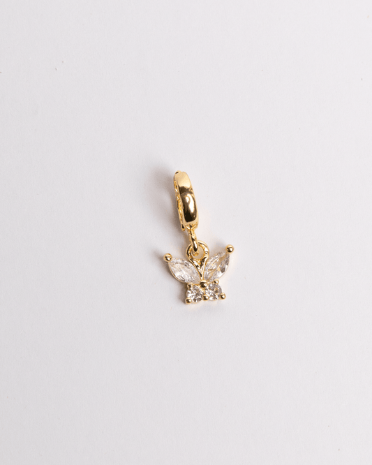 A gold-colored charm in the shape of a butterfly with crystal detailing