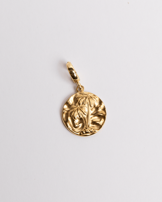 A gold-colored circular charm with a palm design, attached to a small loop for jewelry attachment.