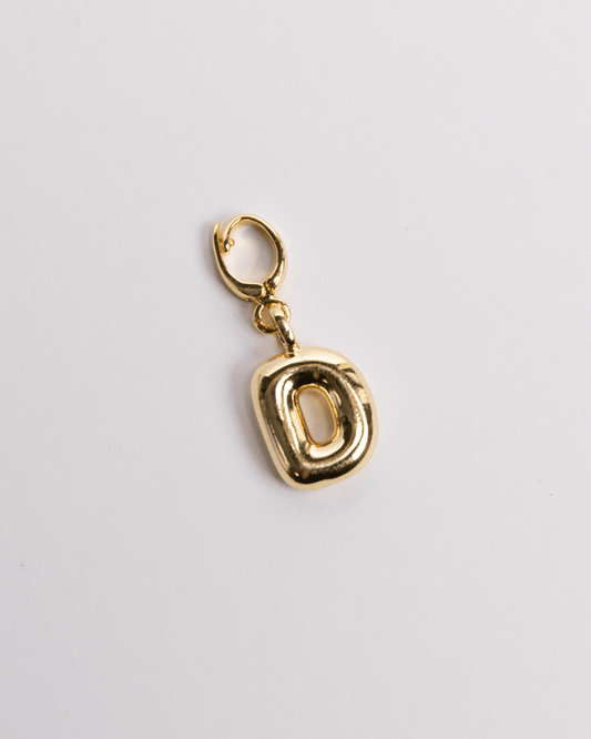 A gold-colored charm in the shape of the letter D with a secure clasp designed for attaching to necklaces or bracelets.