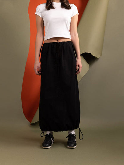 A person wearing a white crop top and the Women's Drawcord Skirt in black by Alpha Industries.