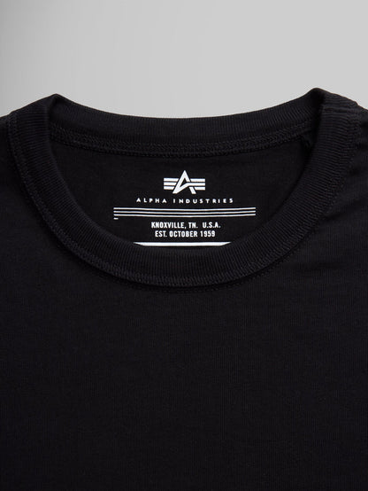 Black Alpha Industries Essential Tee collar and label with brand logo and establishment details.
