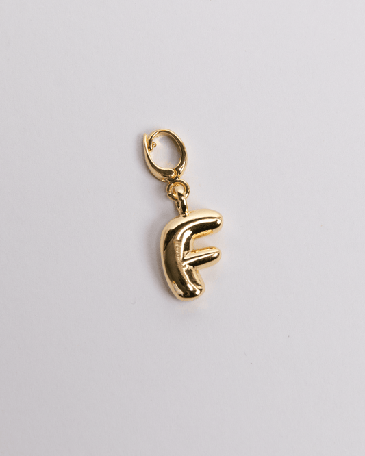 A gold-plated stainless steel charm in the shape of the letter 'F' with a clasp for attaching to jewelry.