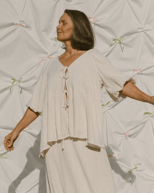 Woman wearing cream coloured crepe oversized flowy shirt & long skirt set.