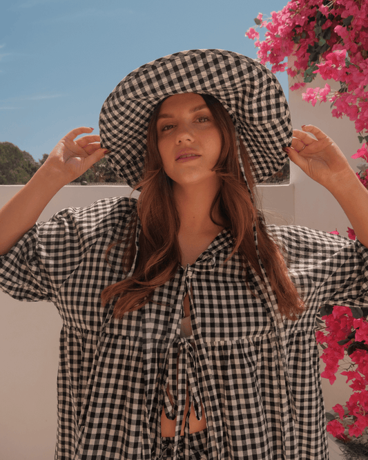 Woman wearing stylish black and white gingham co-ord outfit with a wide-brimmed matching cotton hat.