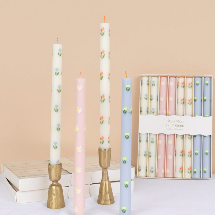 Set of floral-patterned candles with decorative holders on a beige background