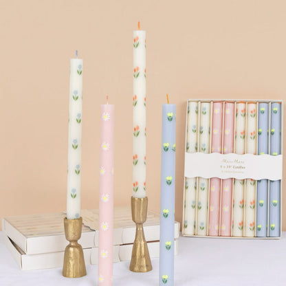 Set of floral-patterned candles with decorative holders on a beige background