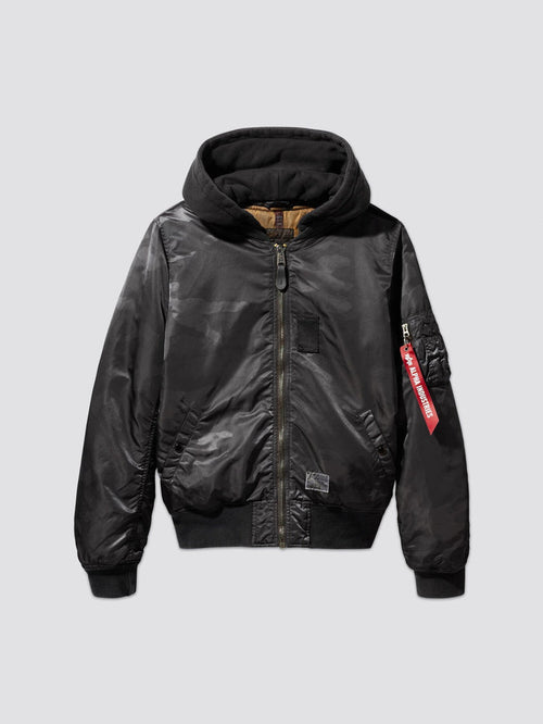 Alpha Industries, Inc.'s MA-1 Hooded Battlewash Bomber Jacket features a front zipper and a distinctive red tag on the sleeve. This design closely follows the iconic MA-1 flight jacket style, offering both warmth and timeless fashion appeal.