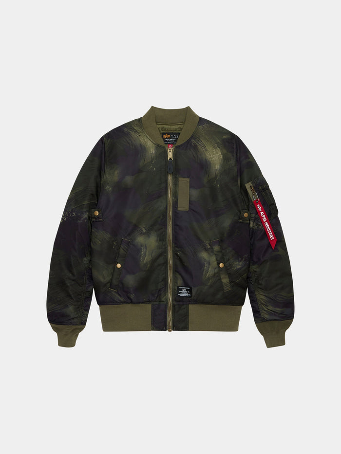 Alpha Industries MA-1 Mod Bomber Jacket in olive rd camo with camouflage print, front zipper, ribbed cuffs, side pockets, utility pocket, red Remove Before Flight tag.