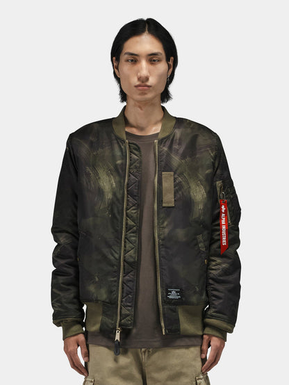 Alpha Industries MA-1 Mod Bomber Jacket in dark green camo with red Remove Before Flight tag and utility pocket.
