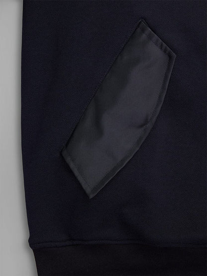 Close-up of a fabric patch pocket on the MA-1 Zip Up Hoodie by Alpha Industries. The pocket is crafted from black French terry fabric, showcasing its texture and stitching details on this dark garment.