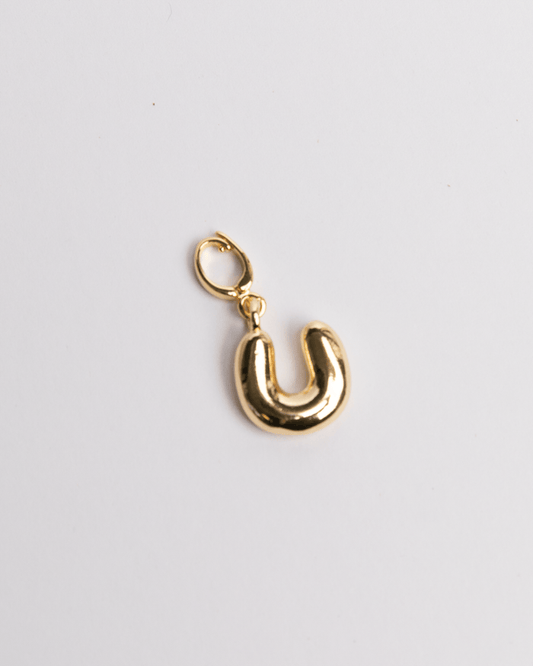 A gold-colored charm in the shape of the letter 'U' with a clasp on a white background.