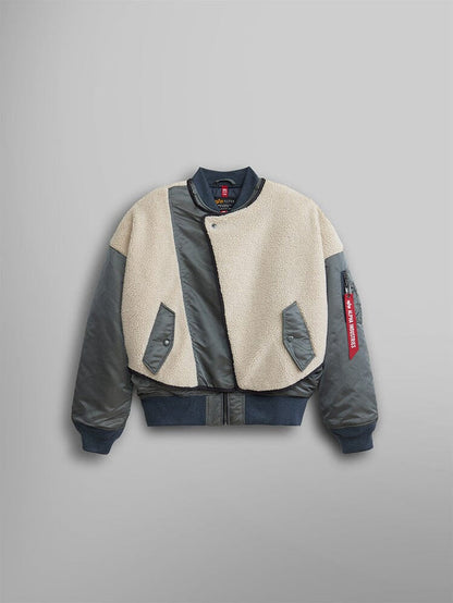 The Alpha Industries Women's B-15 Sherpa Hybrid Bomber Jacket features dark sleeves with a cream faux-shearling front, sherpa paneling, snap buttons, and a distinctive red tag on the sleeve.