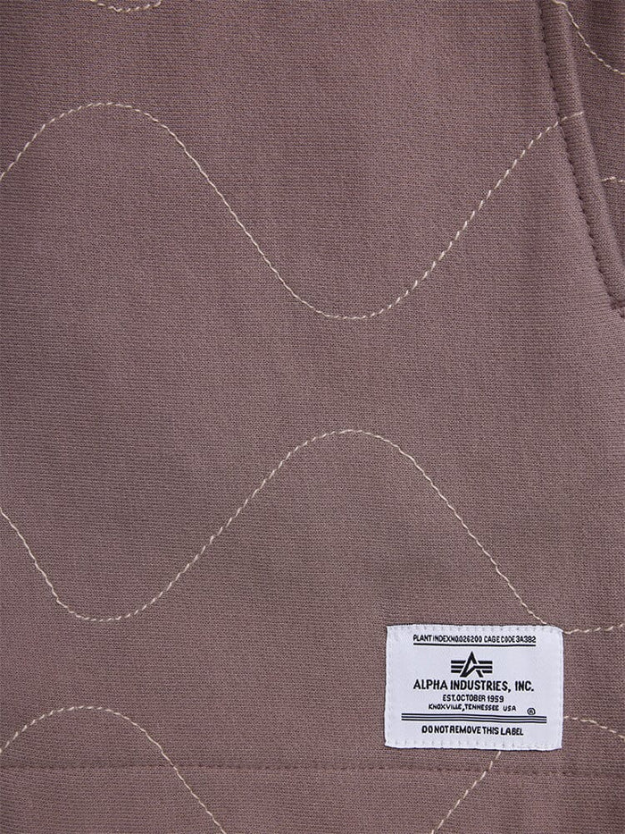 Quilted Shorts by Alpha Industries, brown quilted fabric, visible stitching, white Alpha Industries label at bottom right corner.