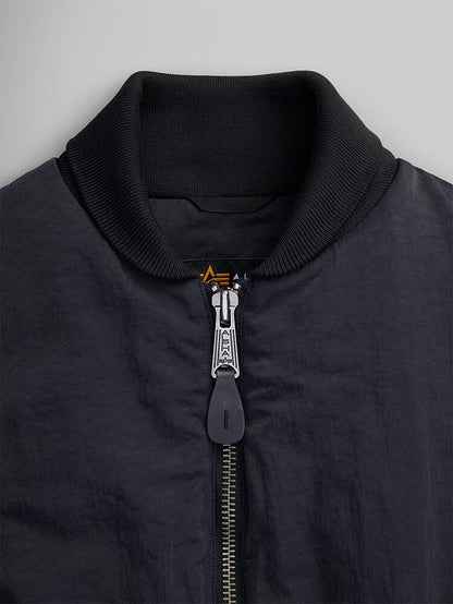 Close-up of the Women's Short Cinched Waist Jacket by Alpha Industries, showcasing its black design with a zipper closure and ribbed collar. The jacket features a quilted lining for added warmth.