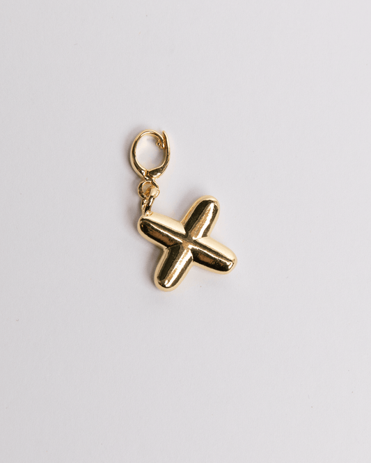 Gold X Letter pendant on a light gray background